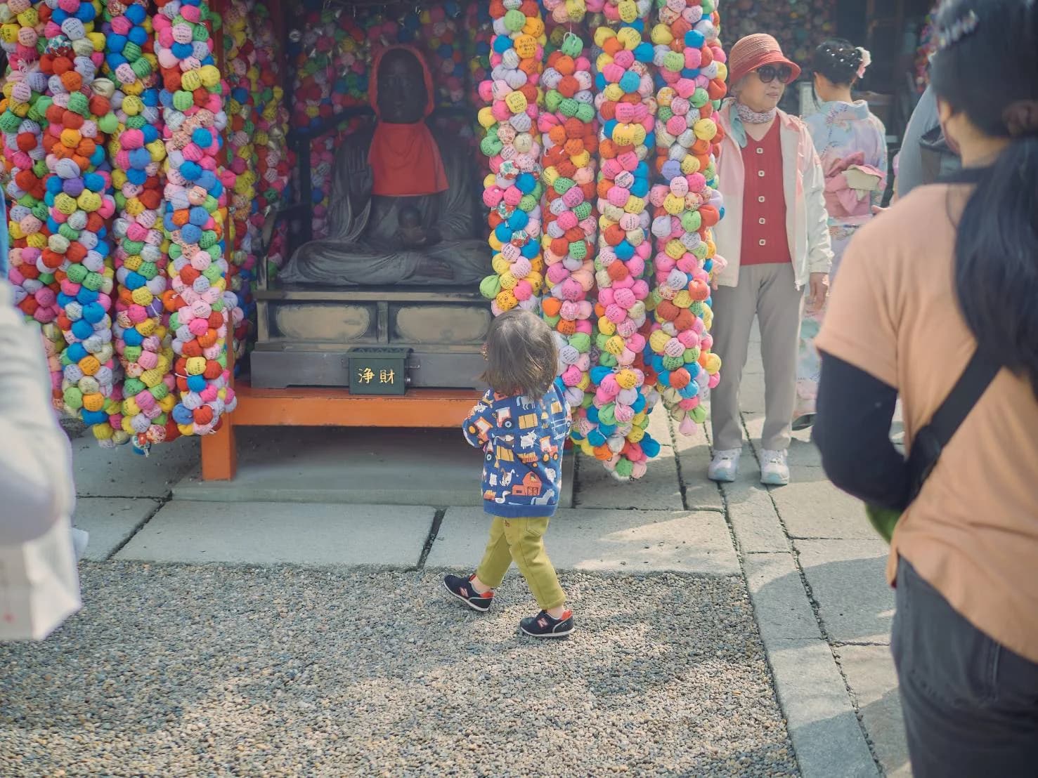 色とりどりの飾りが下がるお堂の前を歩く子ども